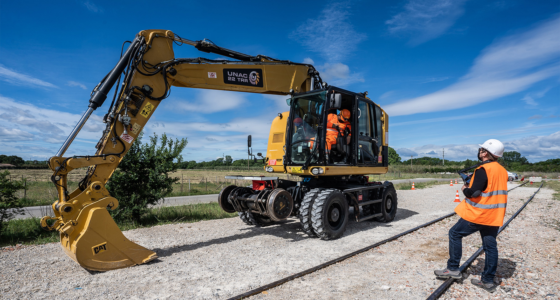 Conducteur en formation CACES R482 catégorie B3 aux commandes d'une pelle rail-route bi-mode sur chantier de pose de voie ferroviaire