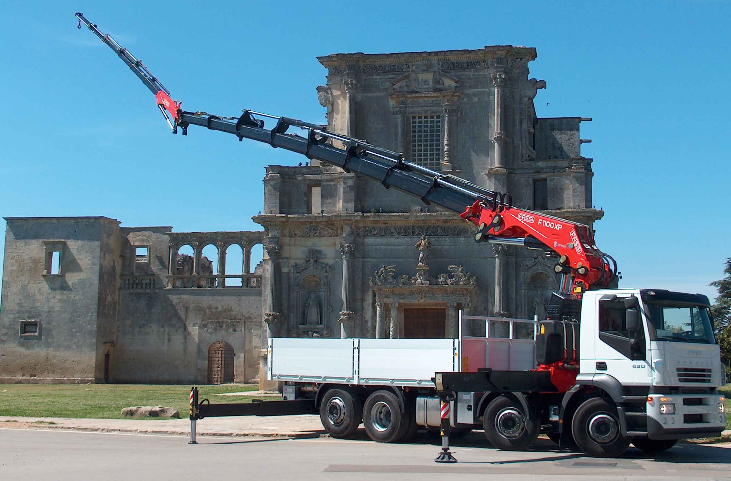 CACES R490 — grue auxiliaire de chantier de travaux publics manipulant une canalisation béton en zone urbaine avec stabilisateurs déployés sur chaussée