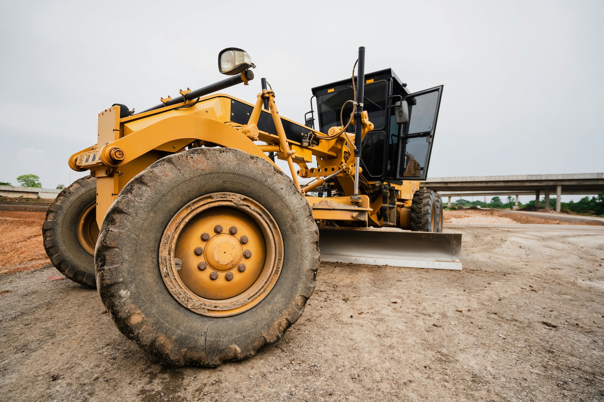 Conducteur en formation CACES R482 catégorie C3 aux commandes d'une décapeuse automotrice en cycle de décapage et transport de terre sur grand chantier de terrassement autoroutier